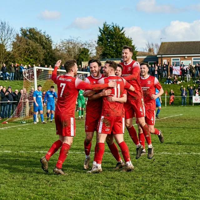 Equipo de fútbol base celebrando un gol